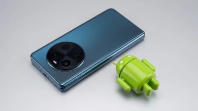 لقطة حقيقية لهاتف vivo X Fold6 الأزرق ومجسم أندرويد مصغر فوق خلفية فضية لتعبر عن تحديث نظام واجهة OriginOS 6