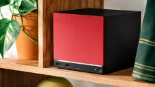 Steam Machine باللونين الأحمر والأسود على رف خشبي داخل غرفة منزلية