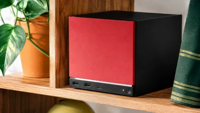 Steam Machine باللونين الأحمر والأسود على رف خشبي داخل غرفة منزلية